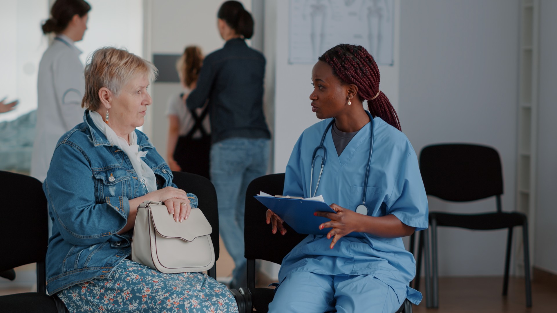 African american nurse explaining diagnosis to elder woman in waiting room